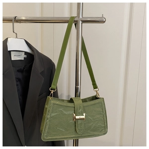Detail of green pleated leather bag with golden buckle on a display rack