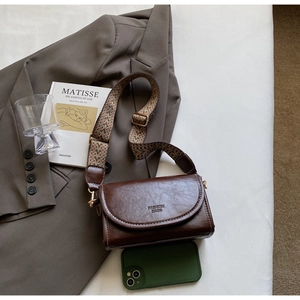 Detail of vintage brown oil leather small square bag with woven strap and embossed logo