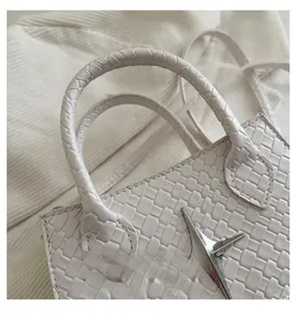 Detail of cream woven handbag featuring square texture and star metal ornament