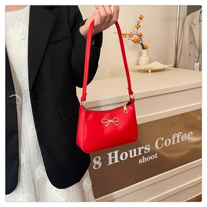 Close-up of vibrant red leather shoulder bag with elegant gold bow metal detail