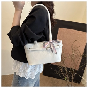 Détail d'un sac cabas en cuir blanc avec un nœud décoratif en soie et une boucle en argent