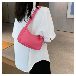 Model wearing a mini rose pink hobo shoulder bag with a sleek minimalist leather design