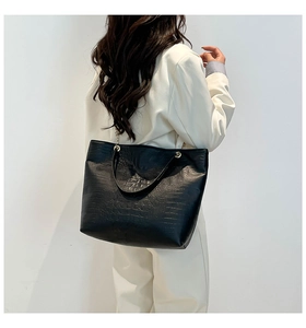 Close-up of black crocodile pattern tote bag showing glossy texture and metal ring detail