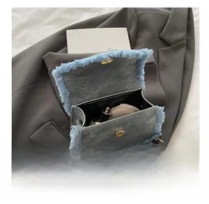 Top view of mini blue denim crossbody bag interior with gold chain and frayed details