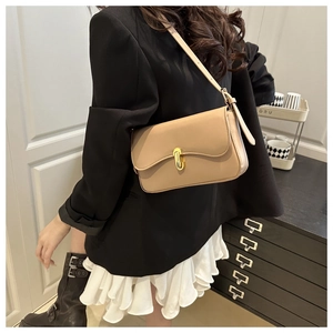 Detailed side view of a beige baguette bag with a gold capsule lock on a model