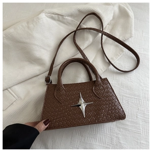 Close-up of brown woven texture bag with silver star emblem on a white fabric background