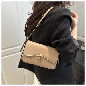 Close-up of minimalist beige baguette bag with wavy flap and gold buckle on blazer