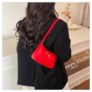 Detail of red synthetic leather shoulder bag with a stylish gold bow metal decoration