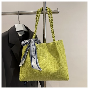 Detail of lime green woven tote bag with a blue printed silk scarf on the braided handle