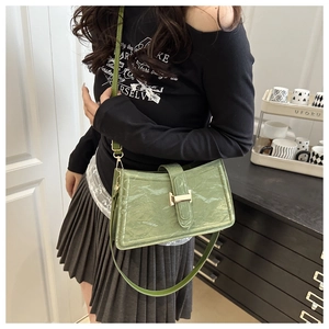 Detail of green pleated leather shoulder bag with gold buckle on model for commuting