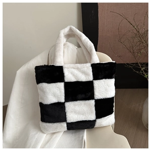 Detailed view of the plush black and white checkerboard tote bag on a cozy chair