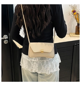 Detail of minimalist cream leather crossbody bag with gold rectangular metal clasp lock
