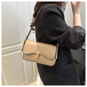 Detail of beige minimalist baguette bag with gold metal clasp and smooth leather texture