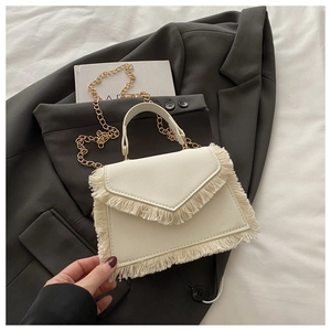 Close-up of off-white crossbody bag with dense fringe details and gold chain strap