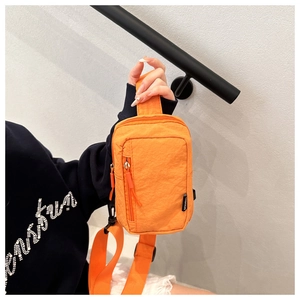 Detail view of bright orange nylon chest bag with dual zippers and fashion label