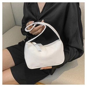 Minimalist white underarm bag with thick handle shown against high contrast outfit