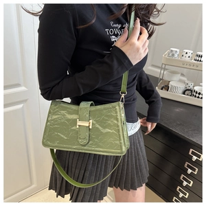 Close-up of green baguette bag featuring glossy wrinkled texture and golden H-buckle detail