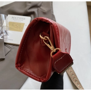 Detail of red leather crossbody bag with golden buckle and jacquard shoulder strap