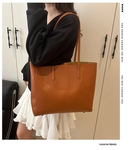 Close-up of a large brown tote bag with decorative stitching and matching shoulder straps