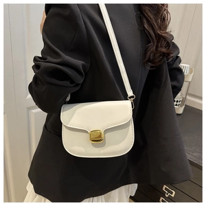 Détail du sac selle en cuir blanc avec boucle dorée et fine bandoulière porté par un mannequin