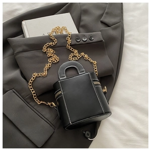 Detail einer Mini-Beuteltasche in Schwarz mit weißen Kontrastnähten und Goldkette