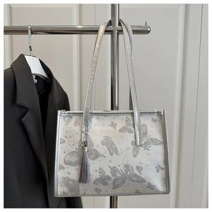 Detail of vintage silver-grey tote bag featuring butterfly embroidery and tassel charm