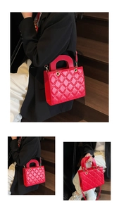 Detail of red quilted patent leather handbag with top handle and crossbody strap