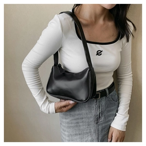 Detail of minimalist black leather underarm bag featuring visible stitching and sleek strap