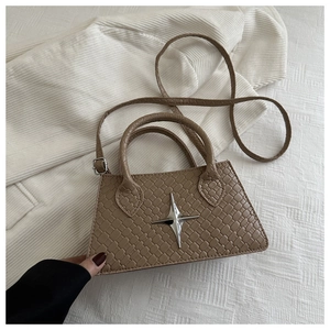 Detail of khaki square tote bag with woven texture, metal star charm, and dual handles