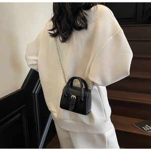 Mini black leather tote bag with silver chain strap shown in a casual lifestyle setting