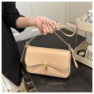 Detail of a beige leather shoulder bag featuring a round golden twist-lock closure