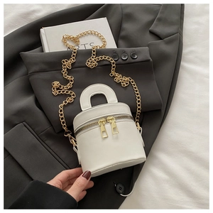 Nahaufnahme weiße Mini-Beuteltasche mit Goldkette auf grauem Sakko-Stoff
