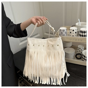 Dettaglio della borsa beige in ecopelle con lunghe frange e occhielli dorati