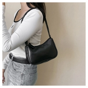 Close-up of small black hobo bag with sleek zipper detail and matte leather finish