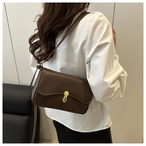 Detail of dark brown matte leather shoulder bag with a gold metal twist lock