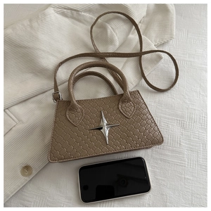 Detailed view of brown woven texture handbag with silver star ornament and shoulder strap