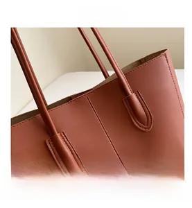 Detail of vintage brown tote bag showing fine stitching and reinforced leather handle join