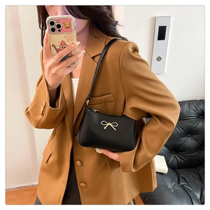 Mirror selfie showing the scale of a black glossy PU shoulder bag with a gold bow detail