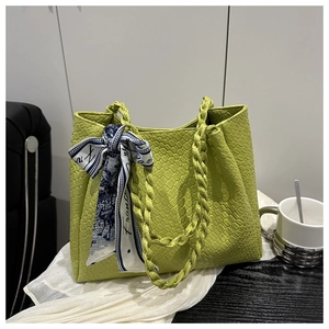 Close-up of green woven tote bag with decorative blue silk scarf on handle