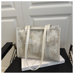 Detail of white tote bag featuring gold butterfly prints and slim double shoulder straps