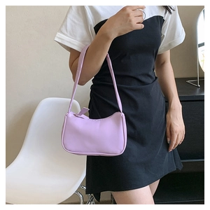 Close-up of lavender underarm baguette bag with leather strap worn by a model