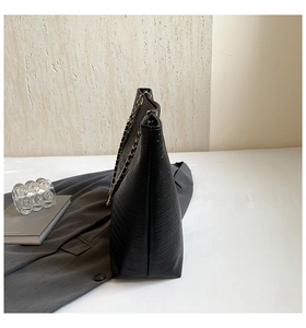 Detail of black faux crocodile skin tote bag with gold metal chain strap and side view