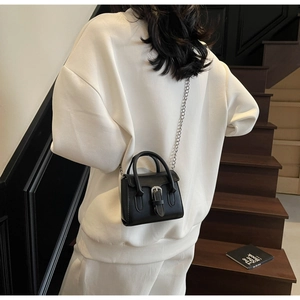Close-up of minimalist black leather mini bag featuring elegant silver chain and metal buckle