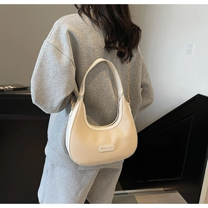 Detail of beige woven hobo bag showing leather chain strap and Miss mini logo on model