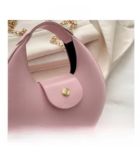Détail du sac demi-lune rose avec fermoir doré, poignée ronde et bandoulière chaîne
