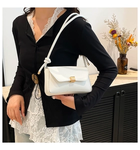 Close-up of white shoulder bag with golden buckle and knotted strap on model