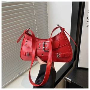 Detail of red punk leather shoulder bag featuring silver metal eyelets and belt buckles
