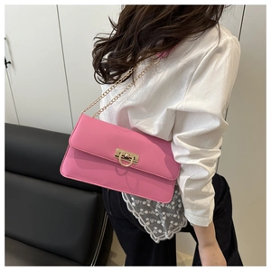 Pink leather shoulder bag with gold chain strap and D-ring buckle on a model
