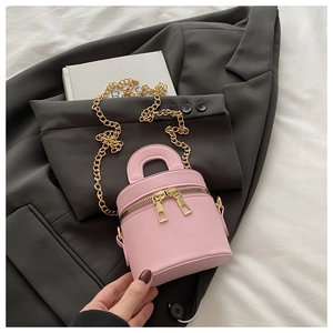 Rosa Mini-Zylindertasche mit Goldkette auf grauem Blazer für einen modernen Mode-Look