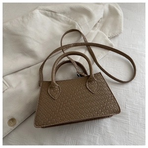Detailed top view of brown crocodile texture mini tote bag on white textured fabric
